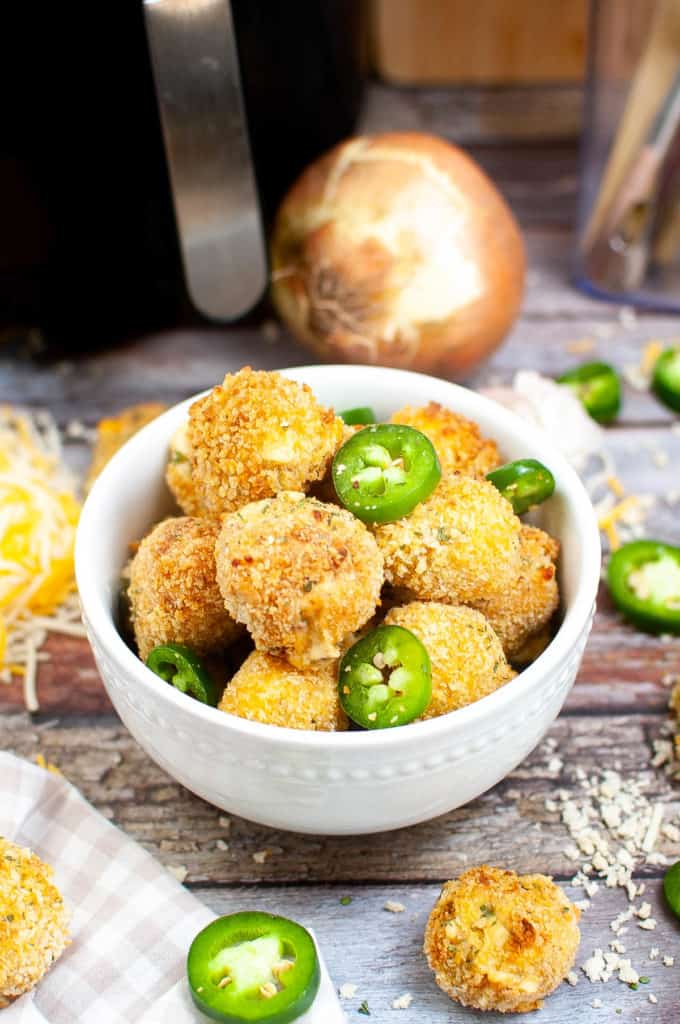 High angle shot of a bowl of jalapeno popper bites with the air fryer in the background.