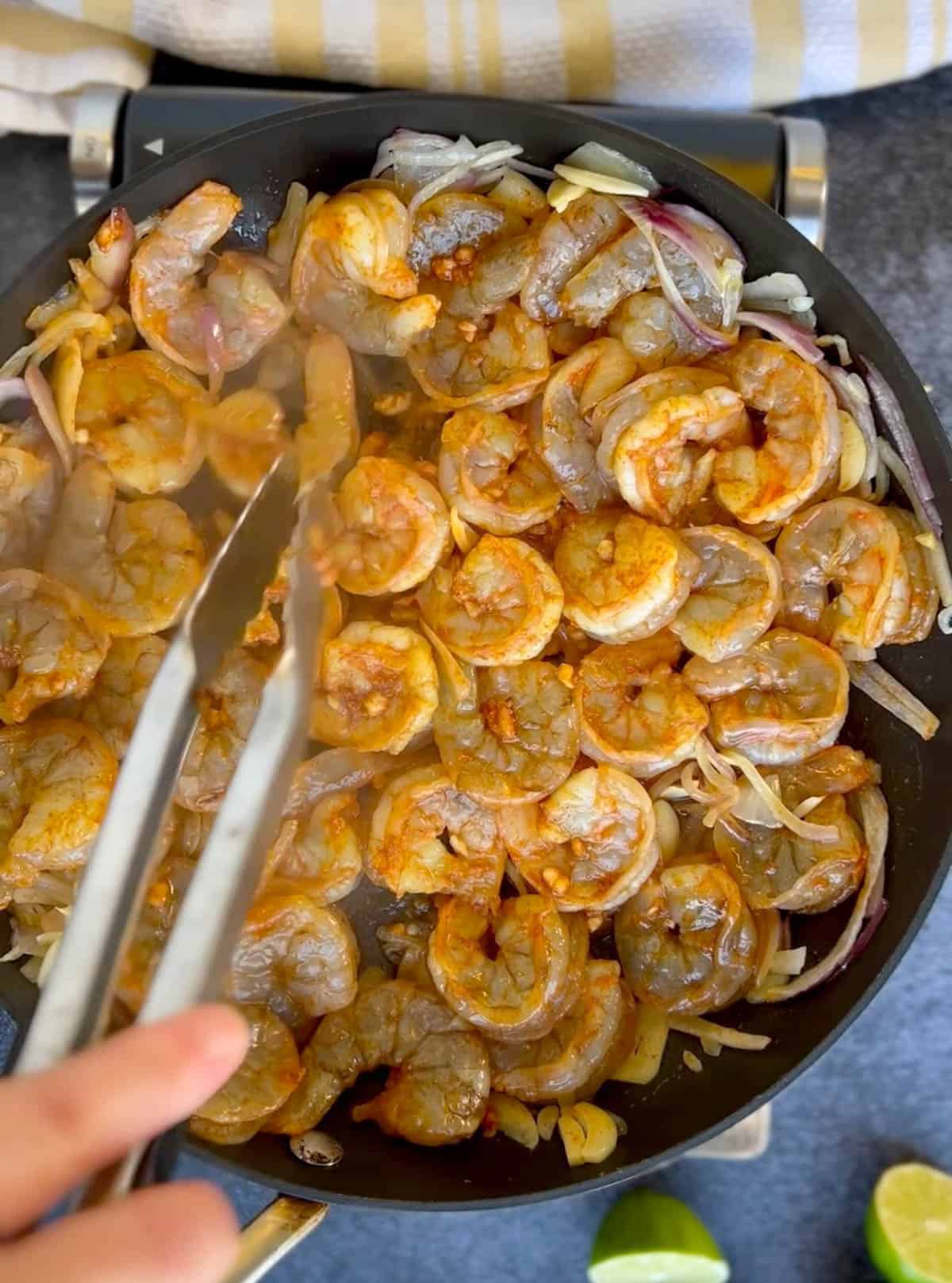 cooking the shrimp in the skillet.
