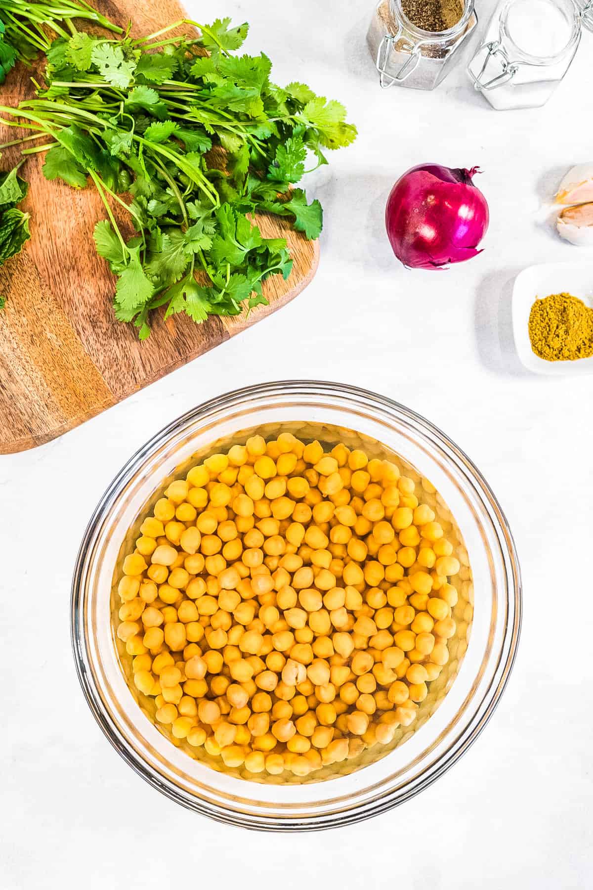 Chickpeas used for an air fryer recipe displayed in a glass bowl on a cutting board.
