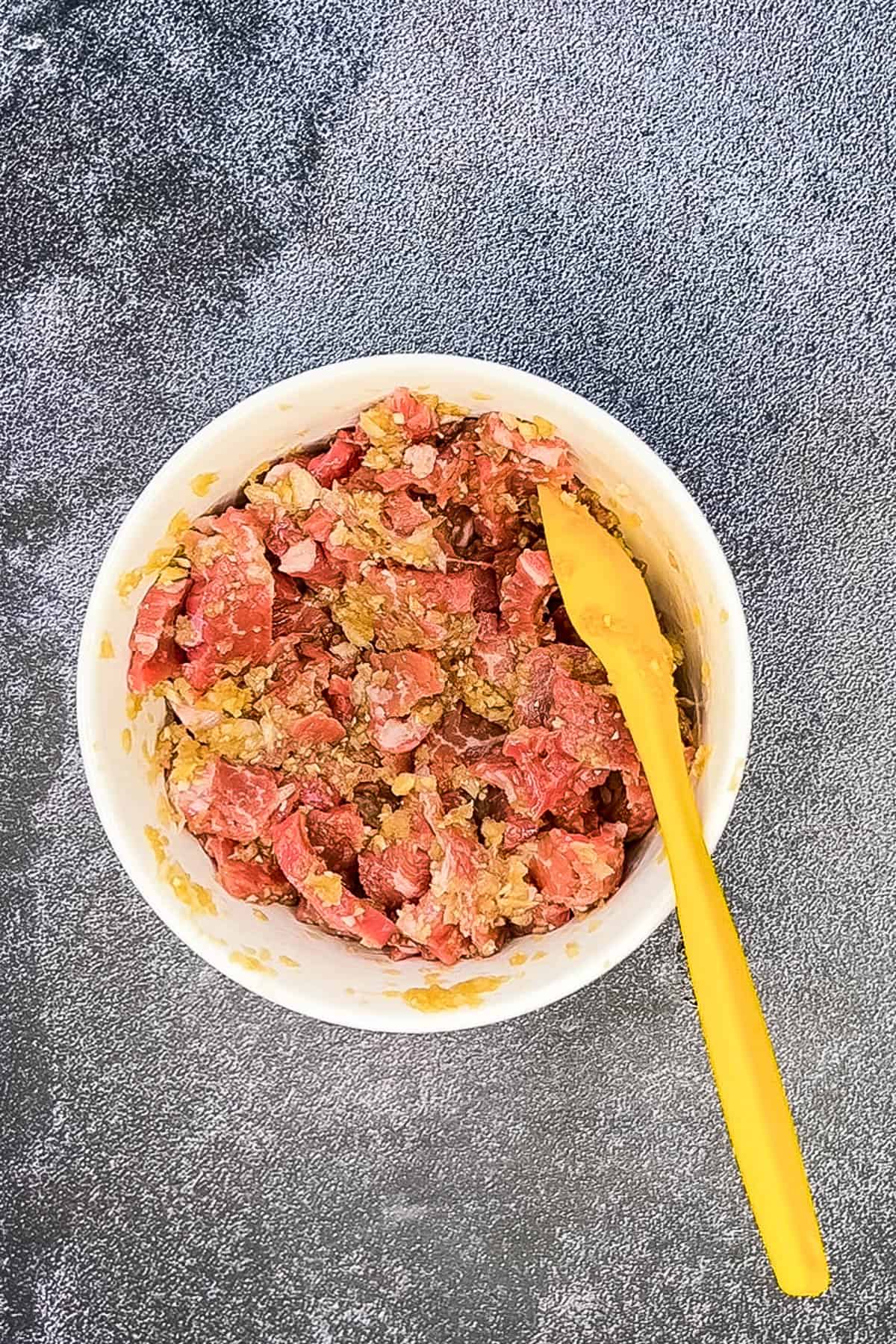 Crispy chilli beef served in a bowl with a yellow spoon.