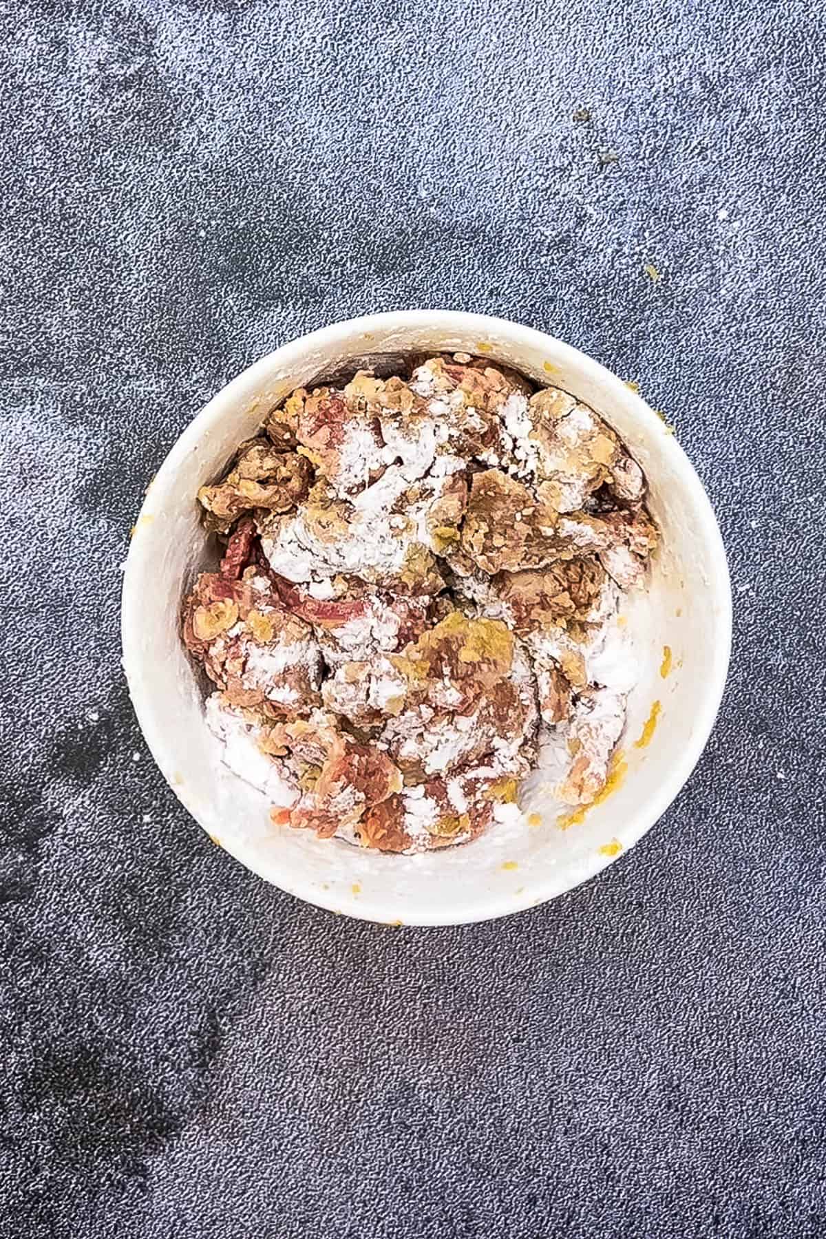 A bowl of crispy food with powdered sugar on top.