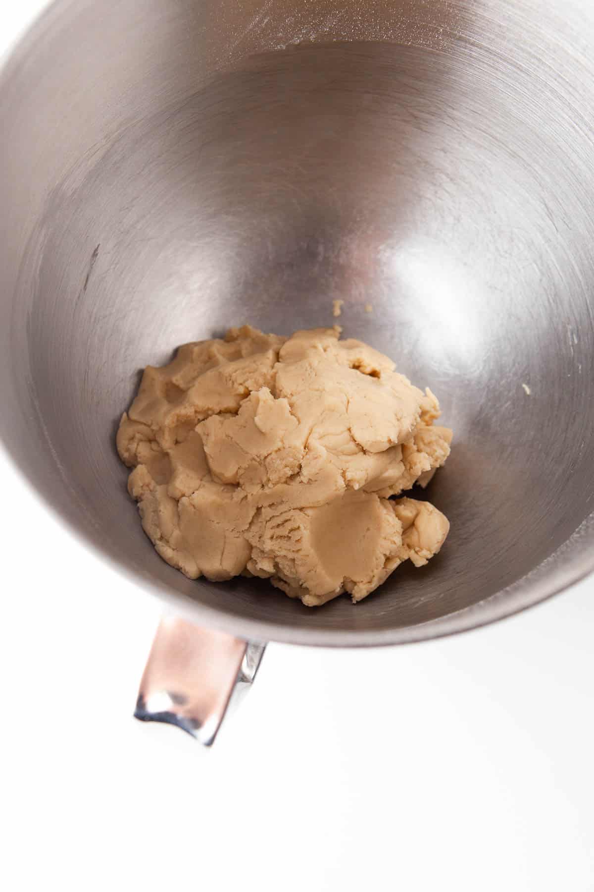 Peanut butter cookie dough with dulce de leche cookies in a mixing bowl.