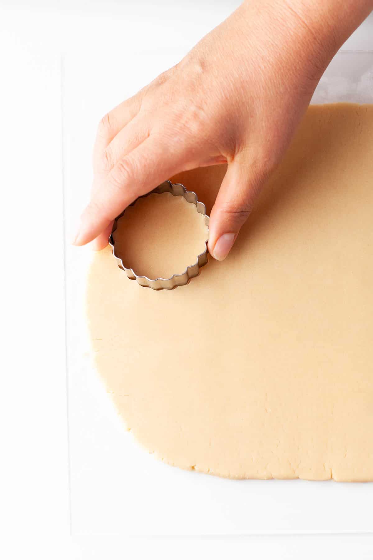 A person cutting dulce de leche cookie dough with a cookie cutter.