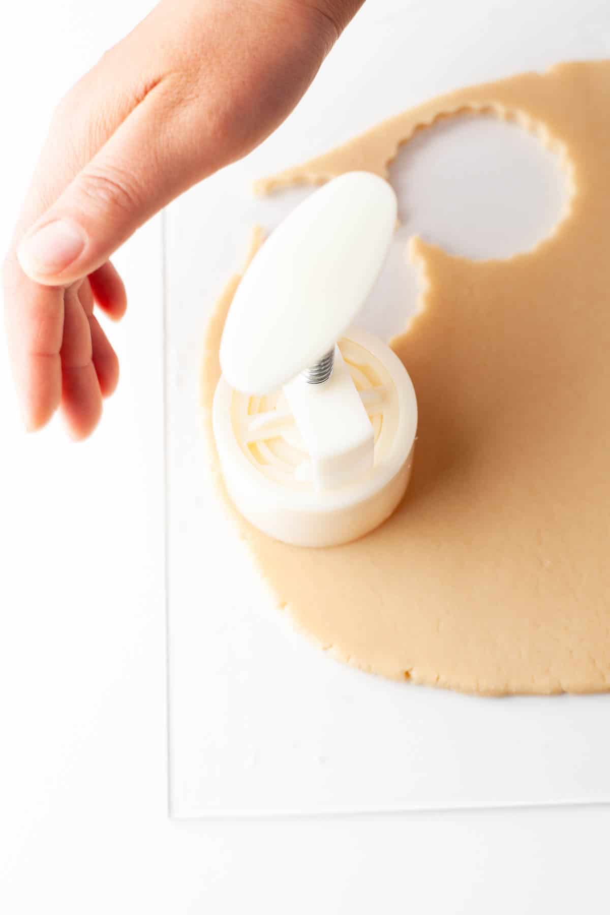 A person using a cookie cutter to make dulce de leche cookies.