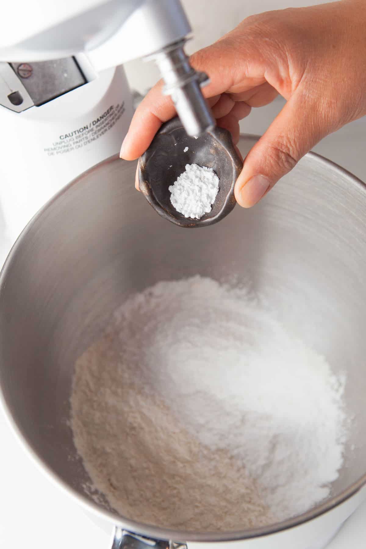 A person preparing dulce de leche cookies by pouring flour into a mixing bowl.