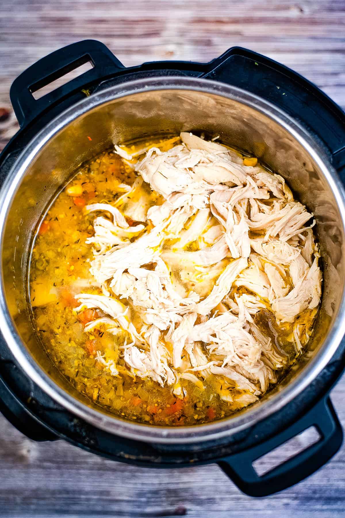 A homemade chicken pot pie soup made quickly in an instant pot, served on a rustic wooden table.