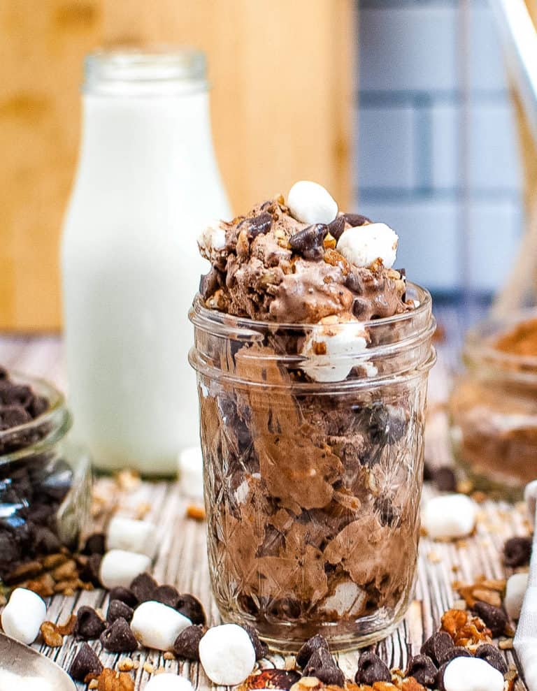 Straight on, close up shot of a jar with rocky road ice cream in it.
