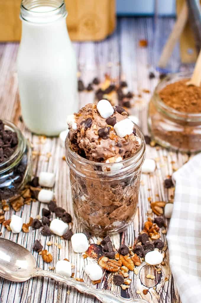 A jar of Rocky Road Ice Cream on a table with ingredients scattered around.