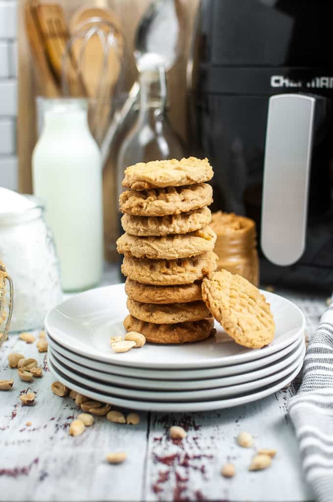 low angle shot of a stack of peanut butter cookies on a plate with an air fryer in the background.