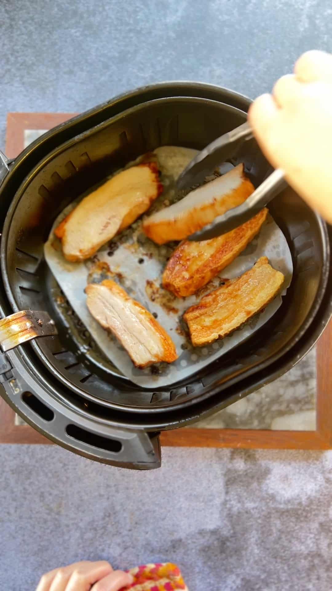 A person air frying pork belly.