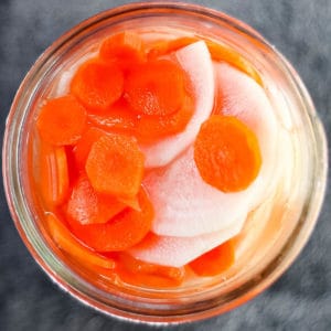 Overhead shot of pickled daikon and carrots in a jar.