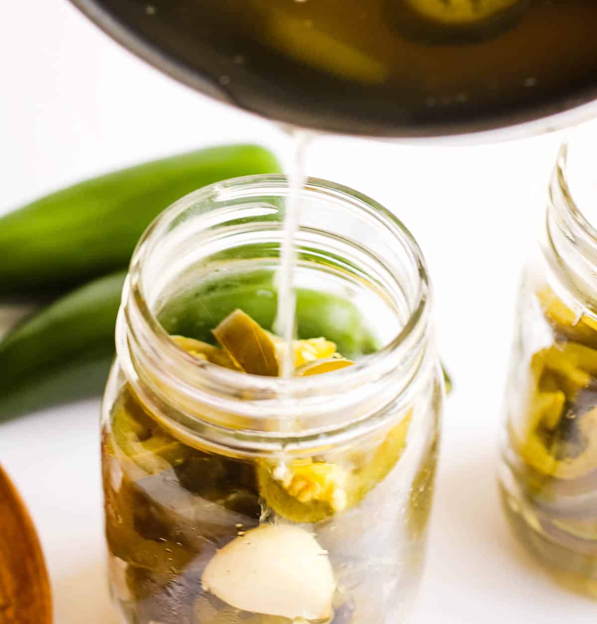 A jar of pickled jalapenos being transferred.