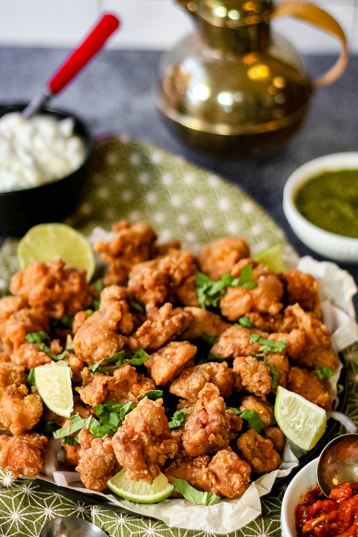 low angle shot of a platter of chicken pakora garnished with lime wedges.