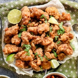 Fried chicken pakora served with lime wedges.
