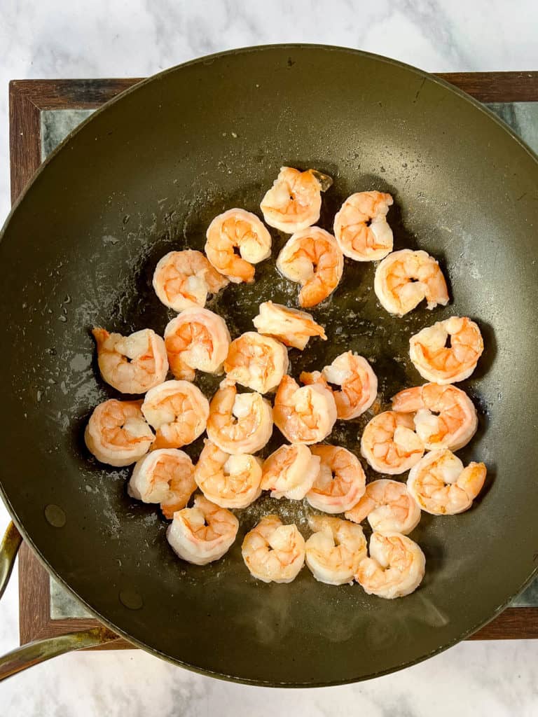 Shrimp yakisoba sizzling on a marble countertop.