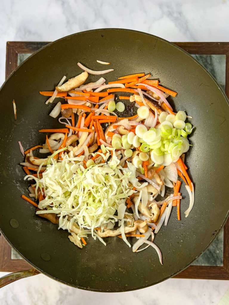 A yakisoba dish with carrots, onions and scallions, stir-fried in a wok.
