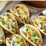 A tray of blackened mahi mahi tacos topped with shredded cabbage, lime wedges, and creamy sauce. Text at the top reads "Blackened Fish Tacos" and a URL "allwaysdelicious.com" is at the bottom.