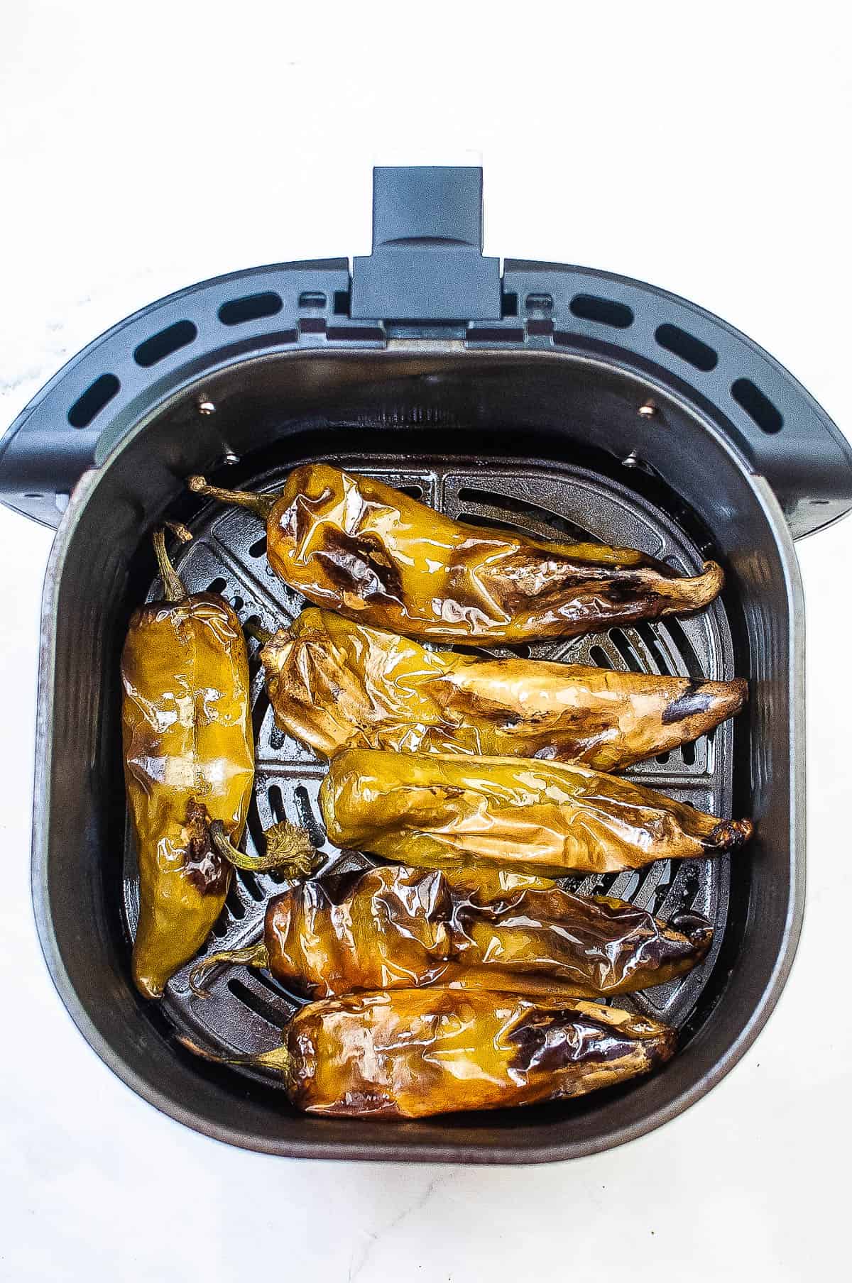 An air fryer filled with roasted hatch chiles.