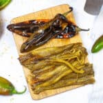 Overhead shot of roasted hatch chiles on a cutting board.
