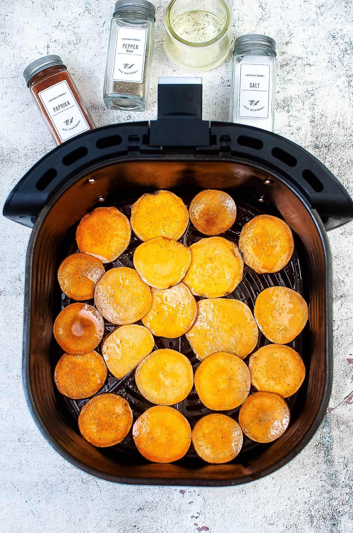 Sweet potato slices arranged in the air fryer basket.