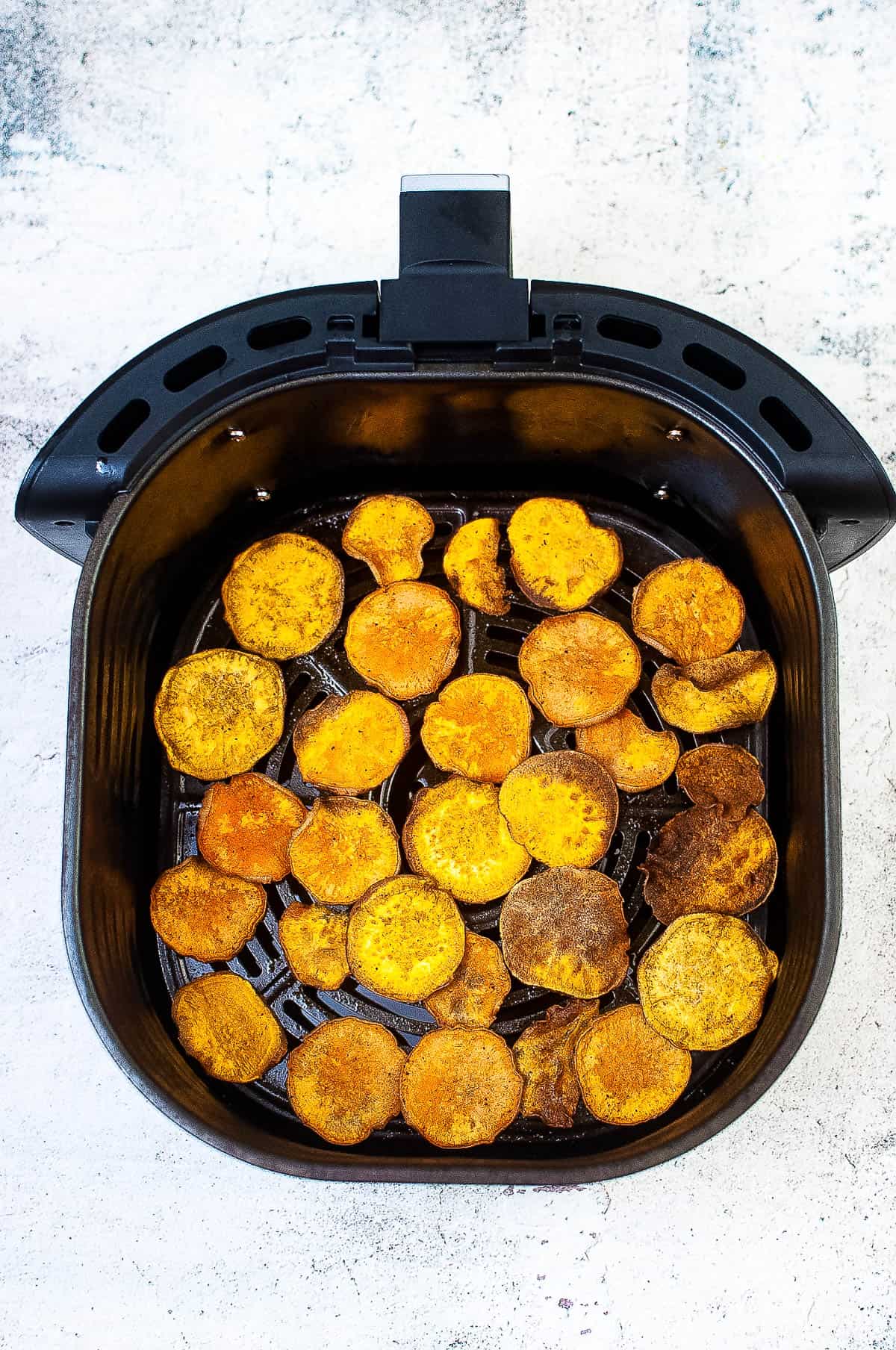 The cooked sweet potato chips in the air fryer basket.