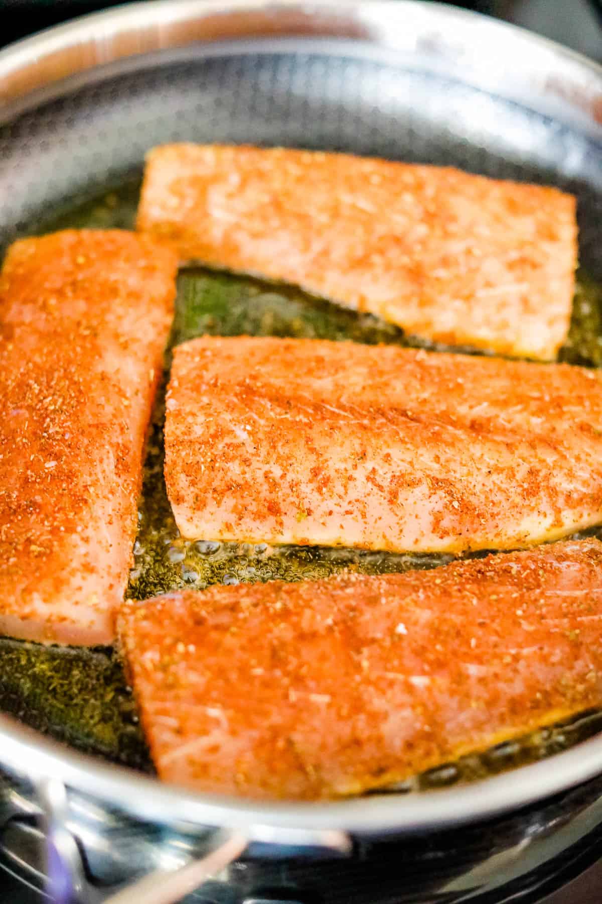 Salmon fillets being cooked in a frying pan, inspired by blackened Mahi Mahi tacos.