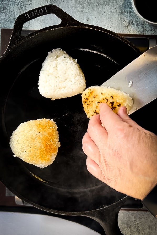 A person frying yaki onigiri in a pan.