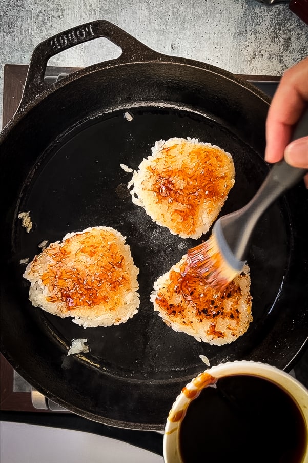 A person is frying yaki onigiri in a pan with oil.