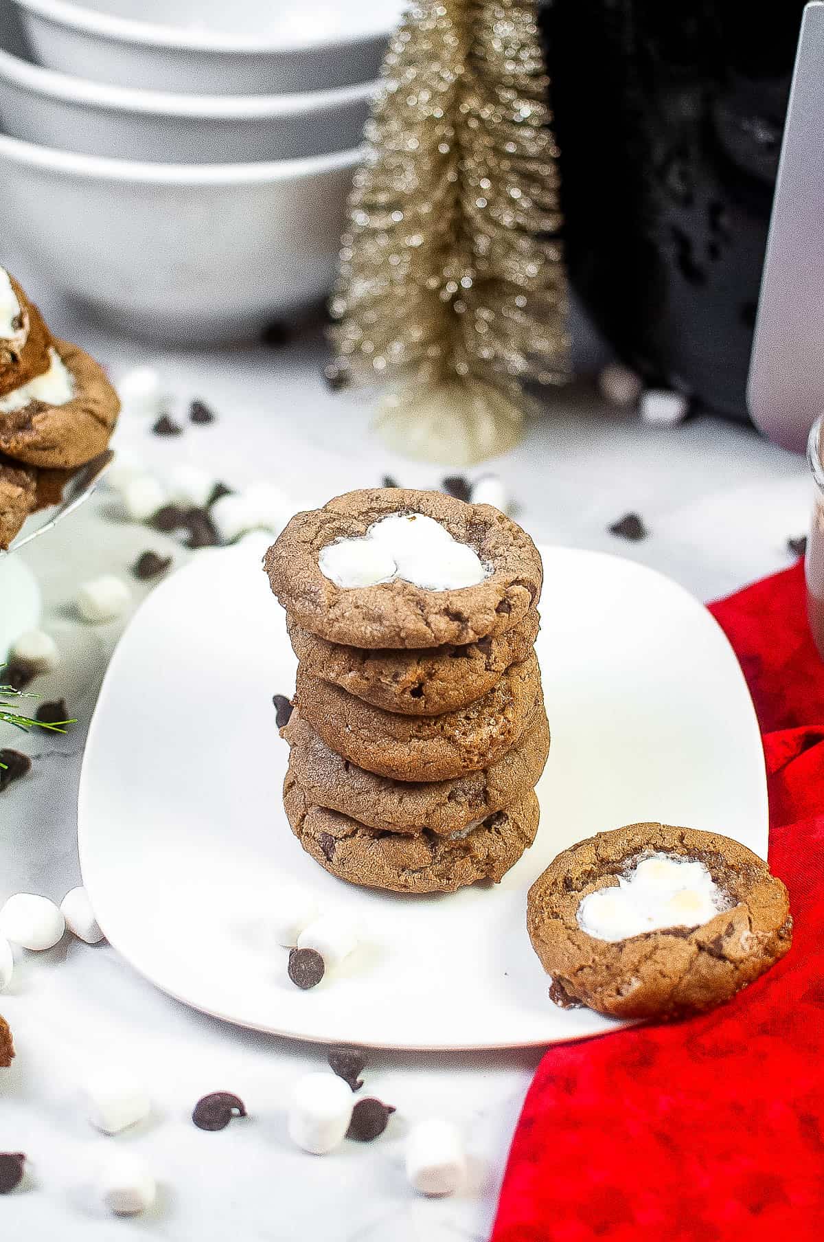 High angle shot of a stack of hot cocoa cookies on a white plate with christmas decorations in the background.