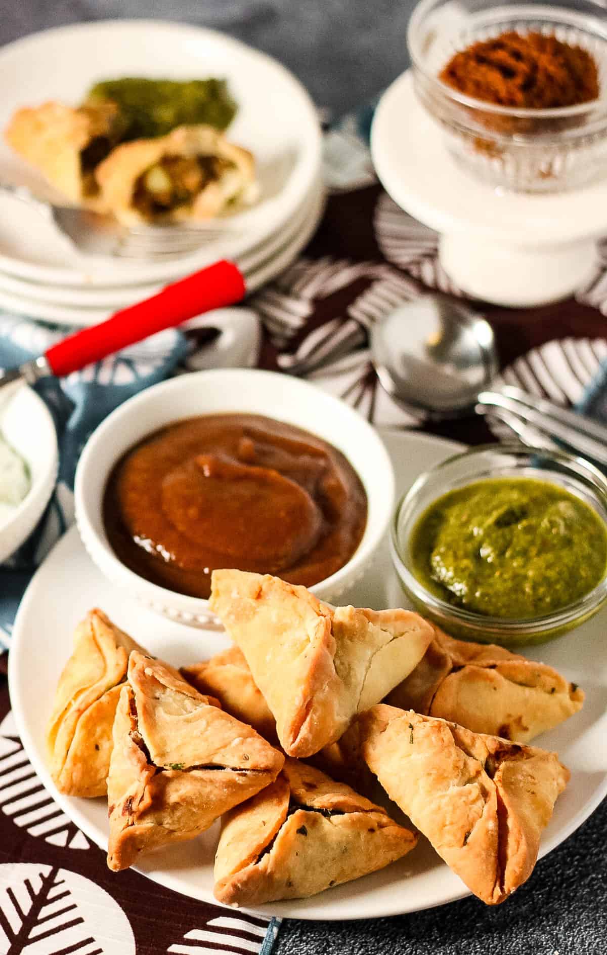 High angle shot of air fried samosas with dipping sauces.