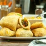 Low angle shot of samosas on a white platter.