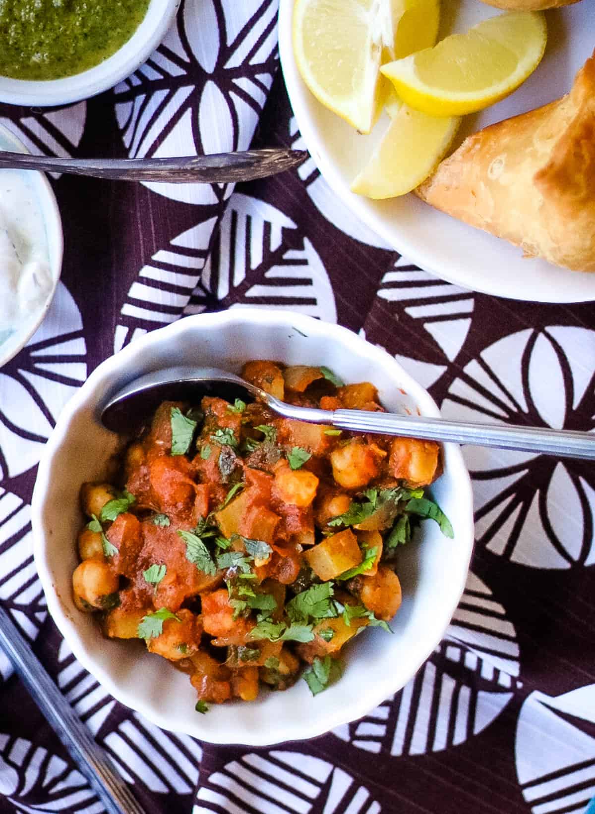 Overhead shot of a bowl of chana aloo masala with a spoon in it.