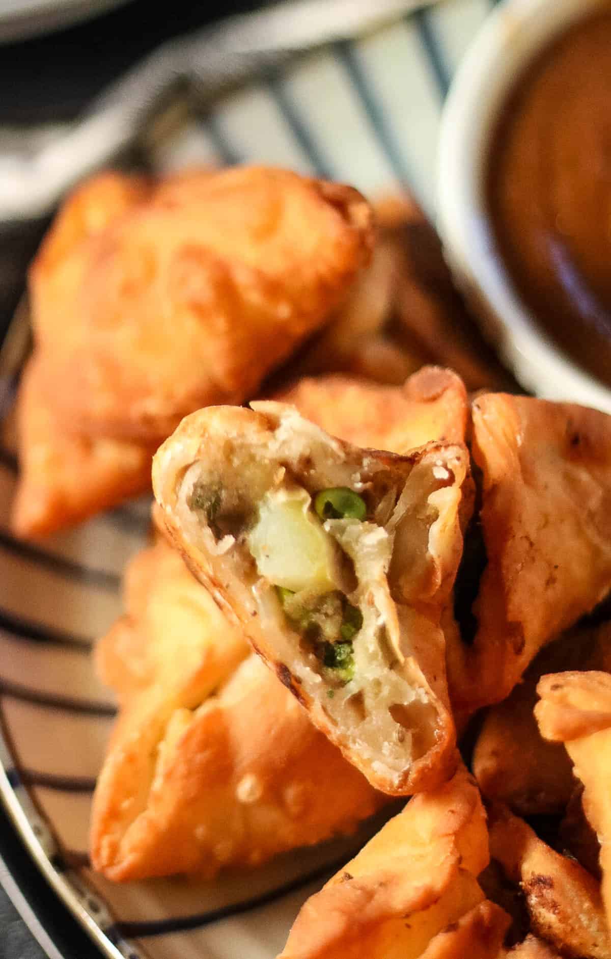 close up shot of the inside of a fried samosa with potato and pea filling.