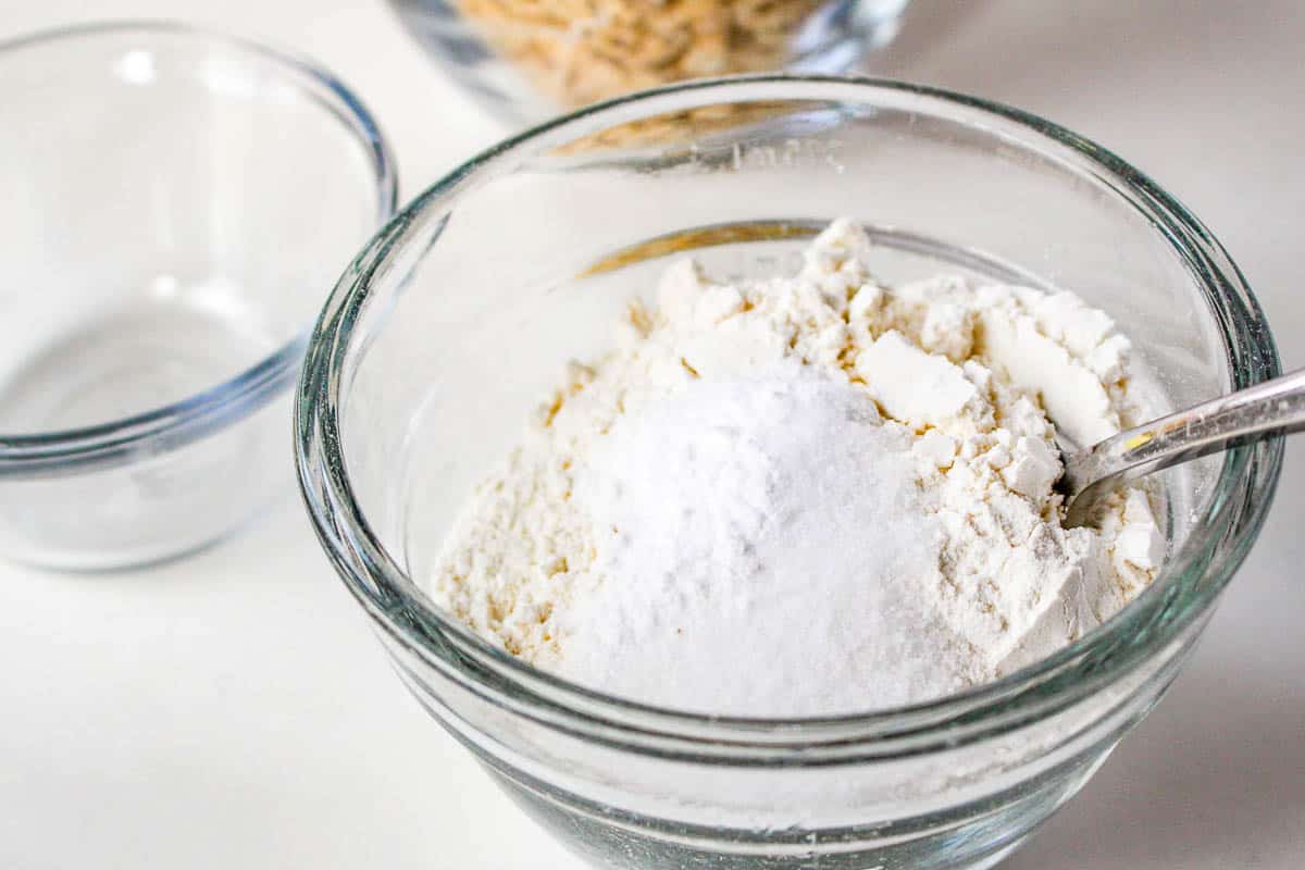 A bowl of flour and a spoon next to it, perfect for making Quaker oatmeal cookies.