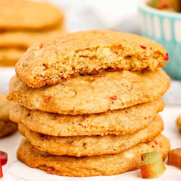 low angle shot of a stack of rhubarb cookies with a broken in half cookie on the top of the stack.