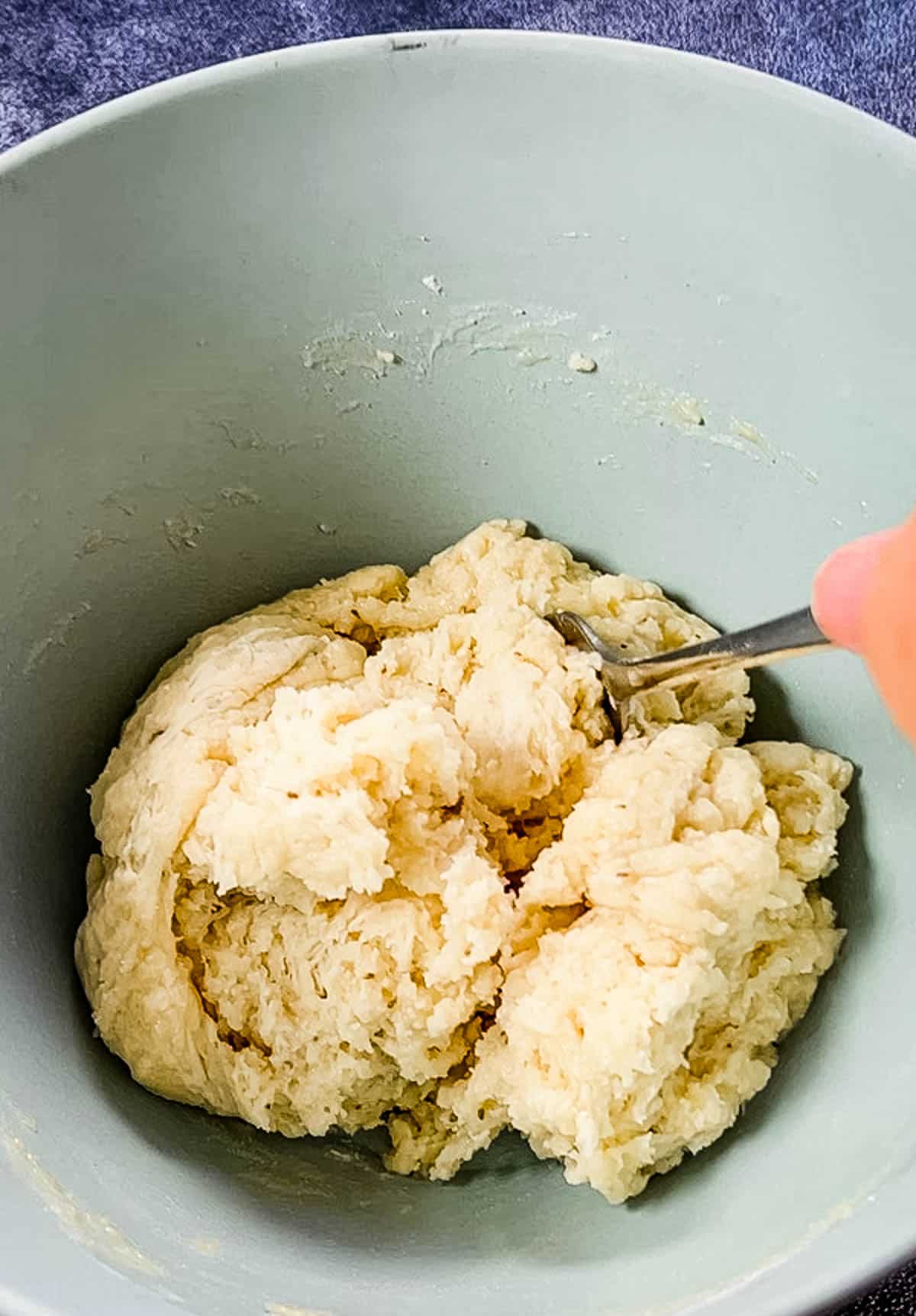 A person preparing samosa dough in a bowl.