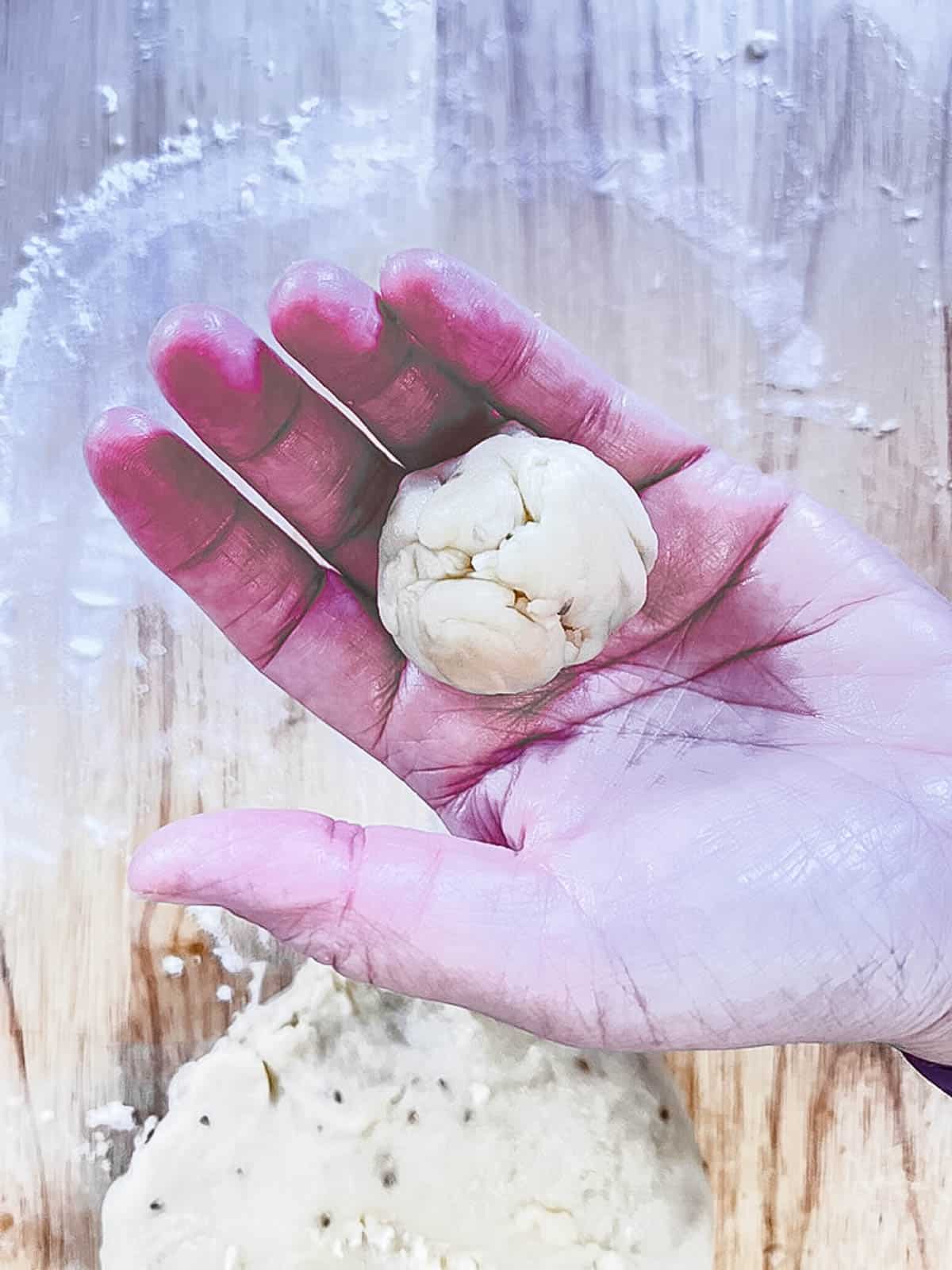 A small ball of samosa dough in a hand.