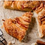 A sliced apple galette rests on a parchment-lined cooling rack, its crust golden brown and apple slices perfectly glazed. Text reads "Apple Galette" and "allwaysdelicious.com" at the bottom, showcasing the delightful beauty of this classic dessert.
