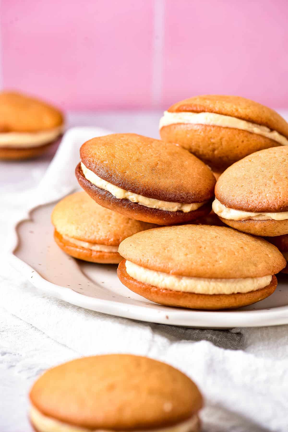 Low angle shot of caramel whoopie pies on a white plate.