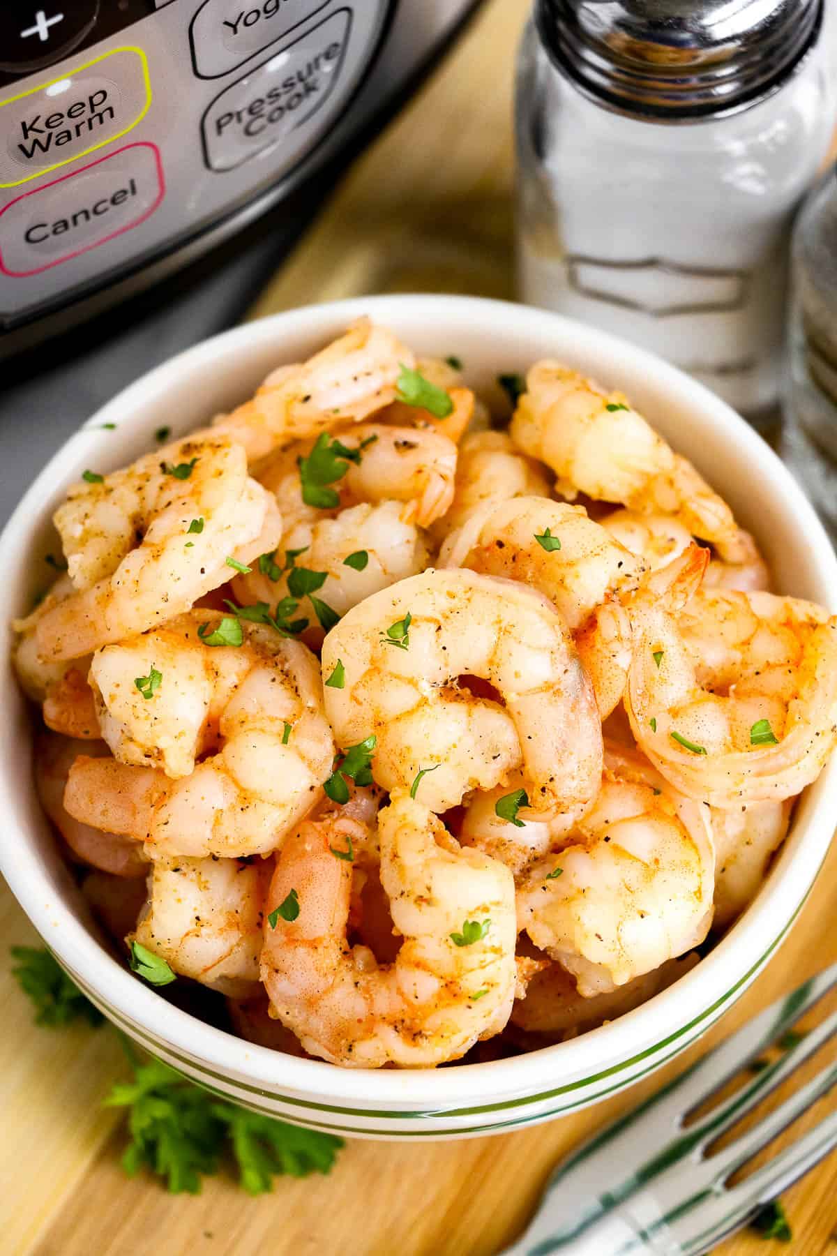 High angle shot of cooked shrimp in a bowl. There is an Instant Pot in the background.