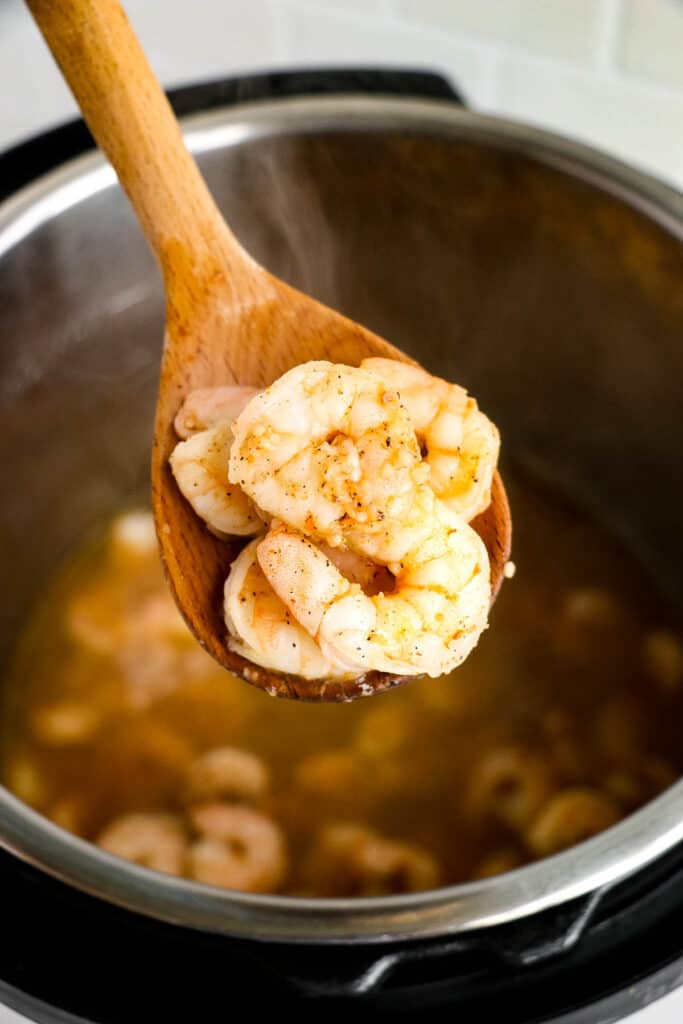Cooked shrimp on a wooden spoon.