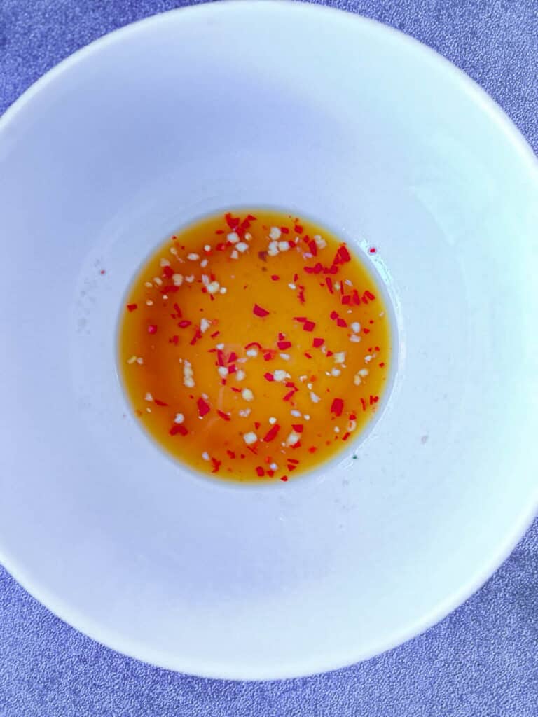 A white bowl with a delicious orange yum Woon Sen sauce.