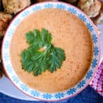 Overhead shot of a bowl of Thai red curry sauce garnished with cilantro leaves.