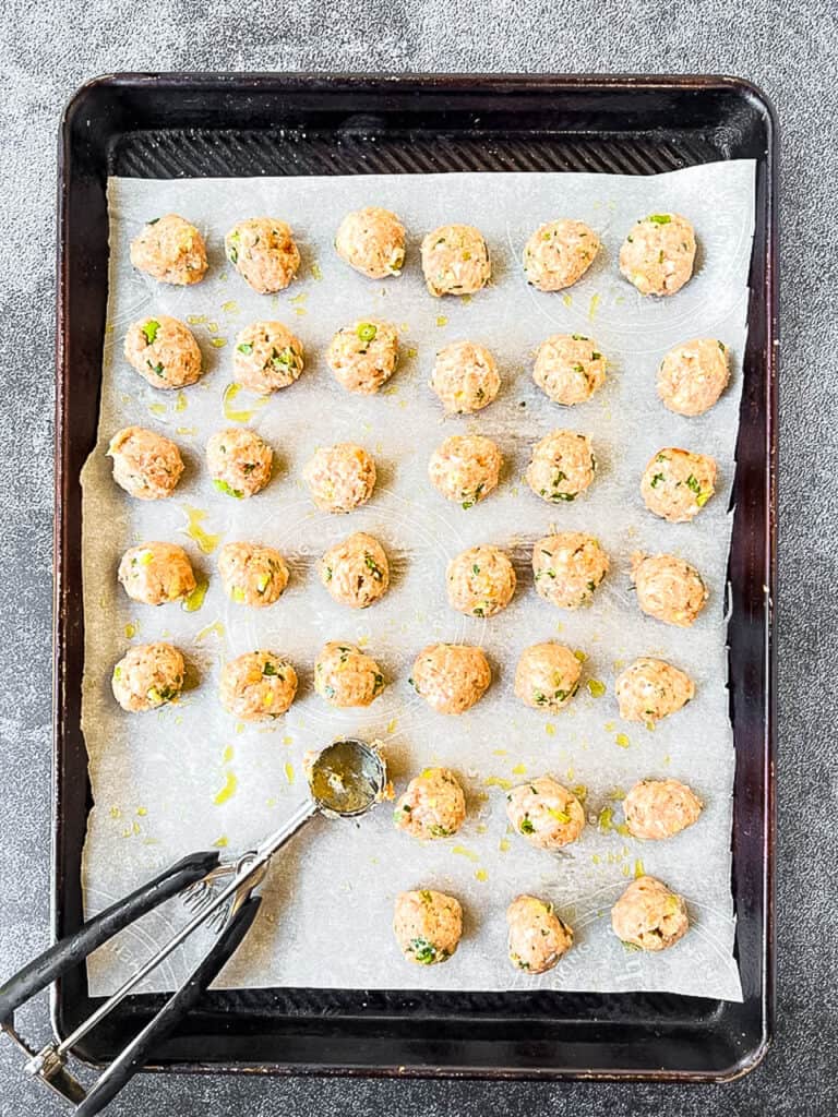 A sheet pan with a tray of Thai turkey meatballs and a scooper.
