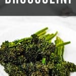 Cooked broccolini on a white plate, with text "air fryer broccolini" above, set against a kitchen counter background.