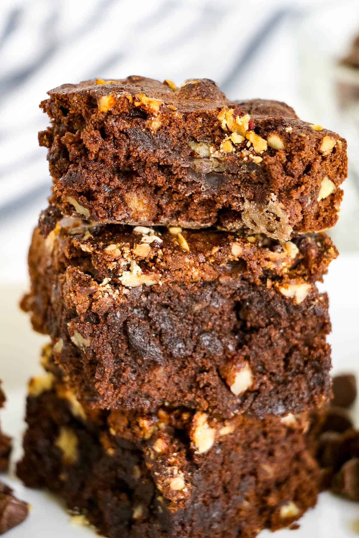 low angle shot of a stack of three fudgy brownies with pecans and caramel.