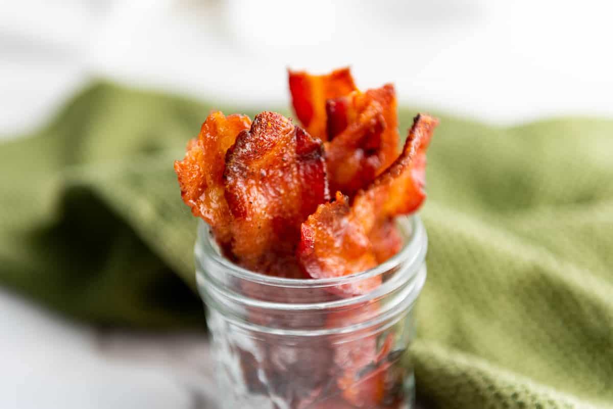 High angle shot of a mason jar filled with strips of candied bacon.