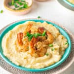 Low angle shot of a plate of shrimp and grits garnished with sliced green onions.