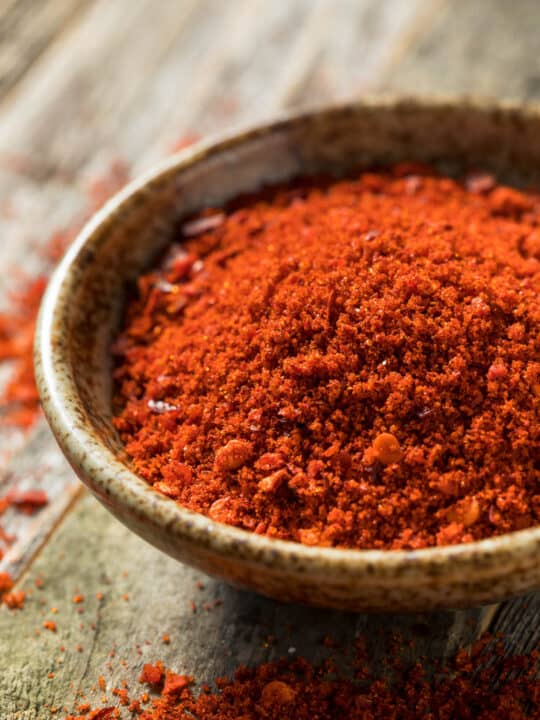 Low angle shot of a bowl of finely ground gochugaru red chili pepper powder.