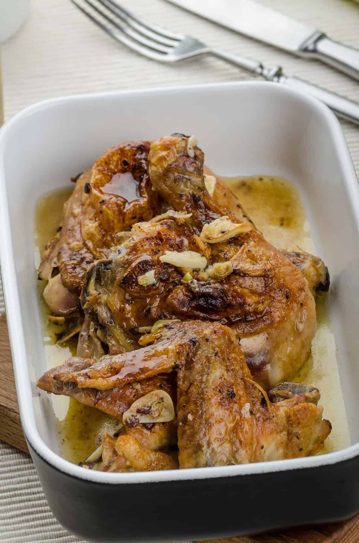 roasted chicken pieces in a baking dish with garlic and herbs.